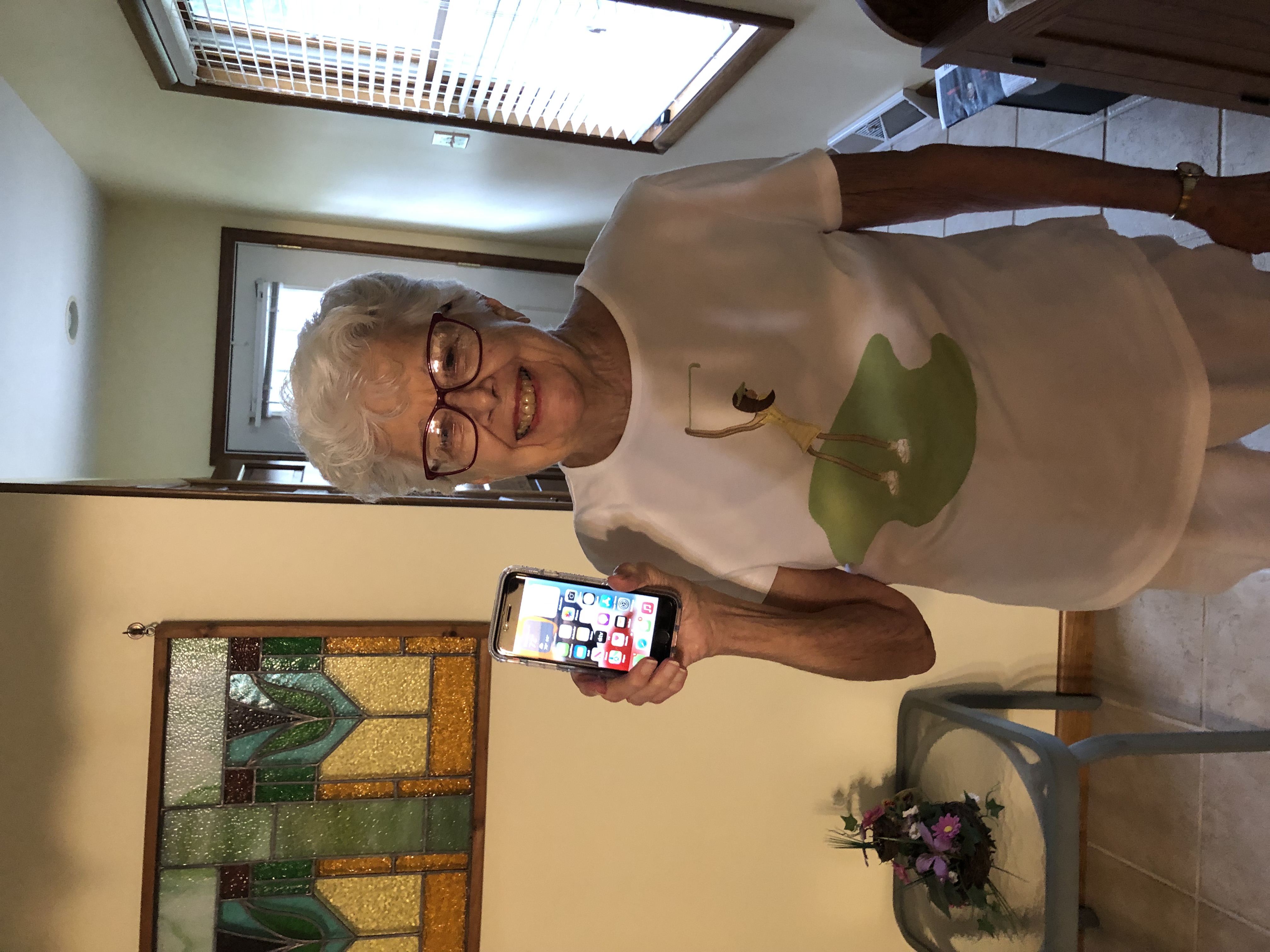 Older woman holding a mobile phone after receiving help using it.