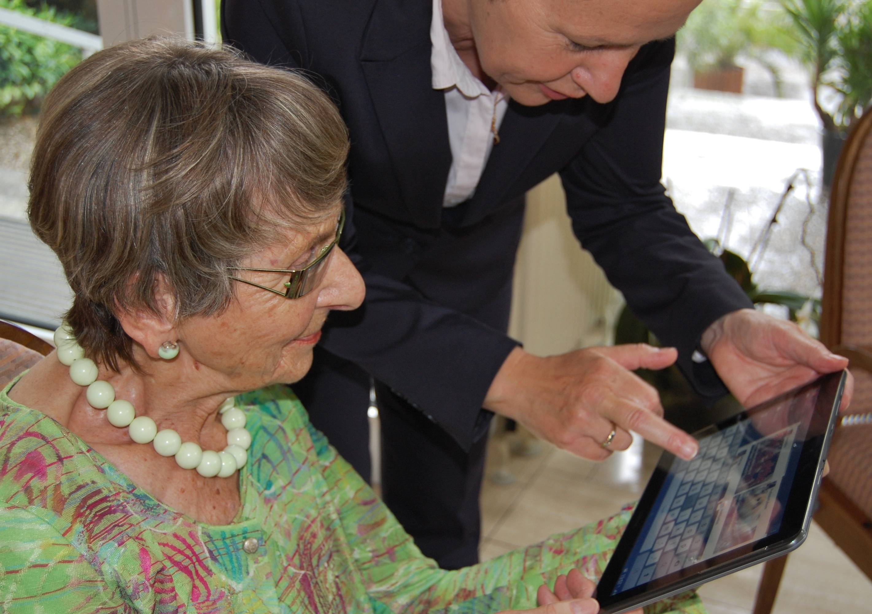 Older person learning to use a tablet computer with support.